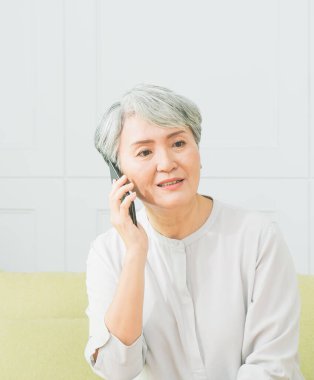 Kıdemli kadın cep telefonunda mutlu bir konuşma yapar..