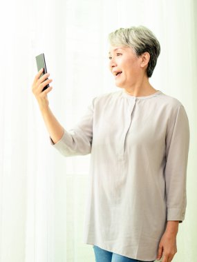 Üst düzey Asyalı kadın cep telefonunu kullanıyor ya da konuşuyor..