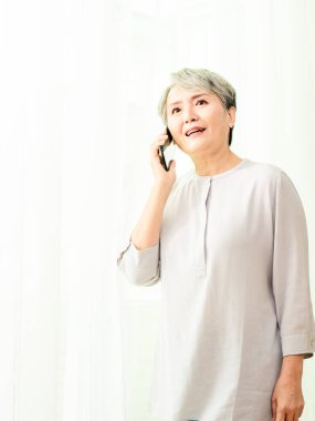 Üst düzey Asyalı kadın cep telefonunu kullanıyor ya da konuşuyor..