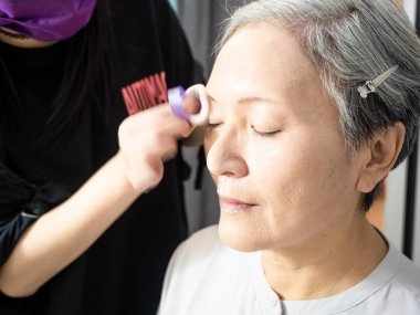 Kıdemli Asyalı kadın ve makyaj sanatçısı..