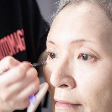 Kıdemli Asyalı kadın ve makyaj sanatçısı..