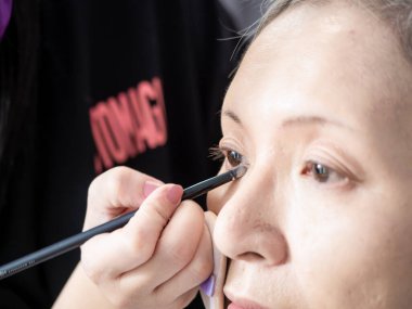 Kıdemli Asyalı kadın ve makyaj sanatçısı..