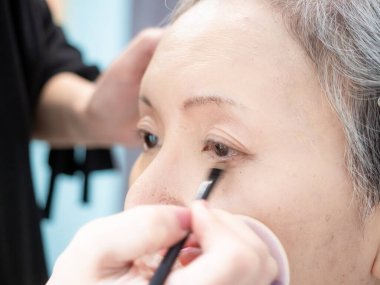 Kıdemli Asyalı kadın ve makyaj sanatçısı..