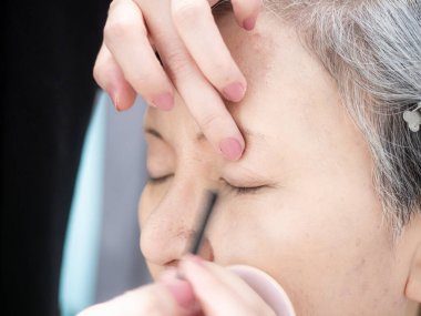 Kıdemli Asyalı kadın ve makyaj sanatçısı..