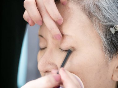 Kıdemli Asyalı kadın ve makyaj sanatçısı..