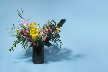 Mavi arka planda bir buket çiçek. Açık mavi arka planda gölgeleri olan çok renkli çiçekler. Ön görünüm.