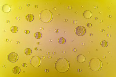 Mor gölgeli ve röfleli jel ve serum köpükleri. Sarı arkaplanda, üst görünümde.