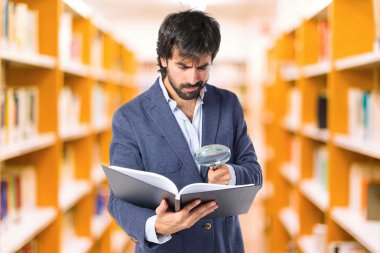 Beyaz arka plan üzerinde bir kitap reding büyüteç ile işadamı