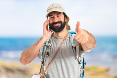 Beyaz arka plan üzerinde konuşmak için telefon backpacker