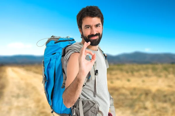 Backpacker making Ok sign over white background — стоковое фото