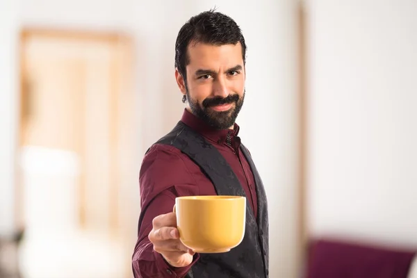 Muž na sobě vestu, držící šálek kávy — Stock fotografie