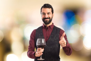 Bir bardak şarap tutan yelek giyen adam 