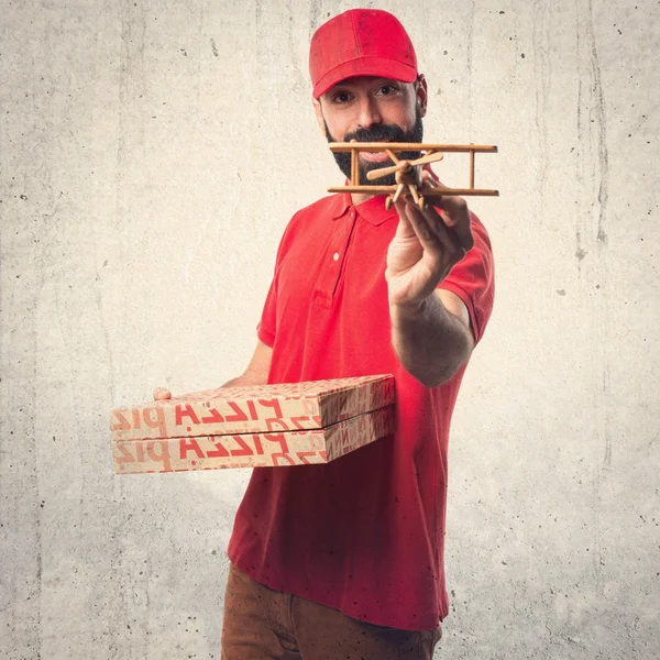 Άτομο παράδοση πίτσα που κρατά ένα ξύλινο παιχνίδι αεροπλάνο — Φωτογραφία Αρχείου