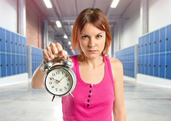 Ernste rothaarige Mädchen hält eine Uhr über weißem Hintergrund — Stockfoto