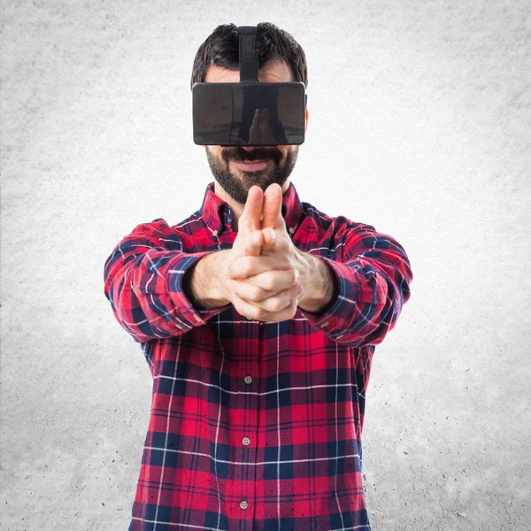Людина використовує VR окуляри роблячи жест зброї — стокове фото