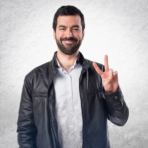 Hombre con chaqueta de cuero haciendo gesto de victoria —  Fotos de Stock