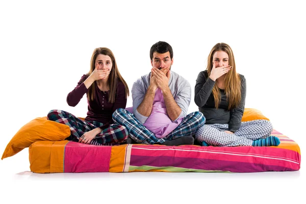 Трое друзей на кровати закрывают рот — стоковое фото