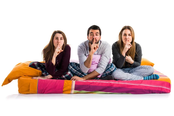 Tres amigos en una cama haciendo un gesto de silencio — Foto de Stock