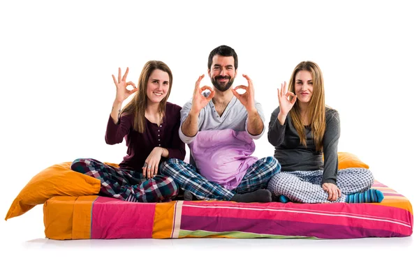 Трое друзей на кровати делают знак ОК — стоковое фото
