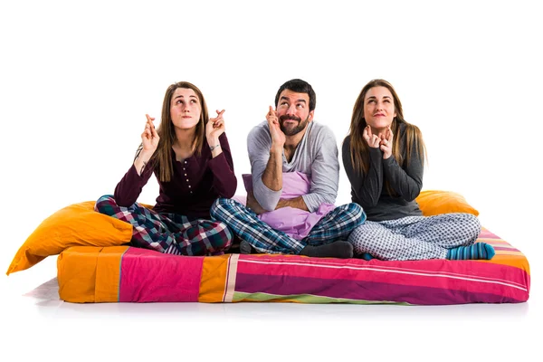 Tre amici su un letto con le dita incrociate — Foto Stock