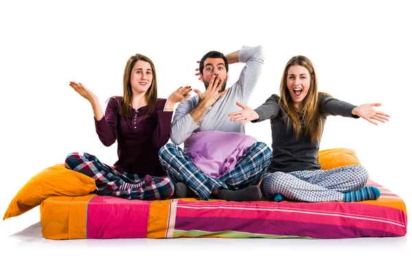 Tre amici su un letto che fanno un gesto a sorpresa — Foto Stock