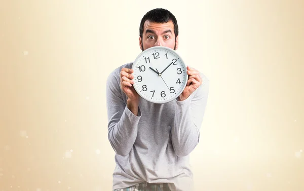 Mann im Schlafanzug hält Uhr — Stockfoto