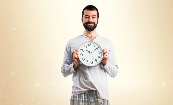 Человек в пижаме держит часы — стоковое фото