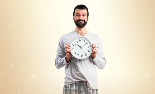 Homme en pyjama tenant l'horloge — Photo