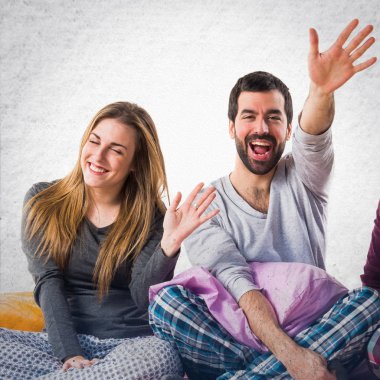 Bir yatak selamlayan üzerinde üç arkadaş