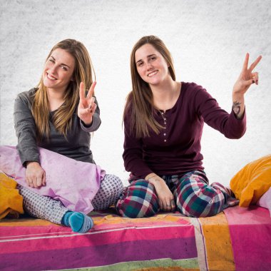 Kız yatakta zafer jest yapıyor