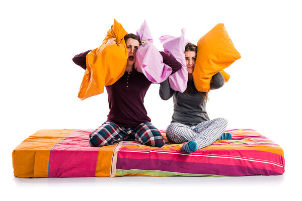 Sisters on bed over isolated background