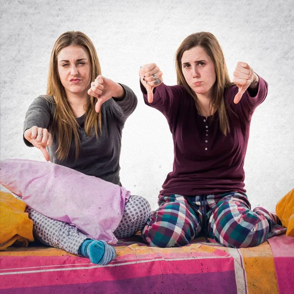 Sisters on bed doing bad signal — Stock Photo, Image