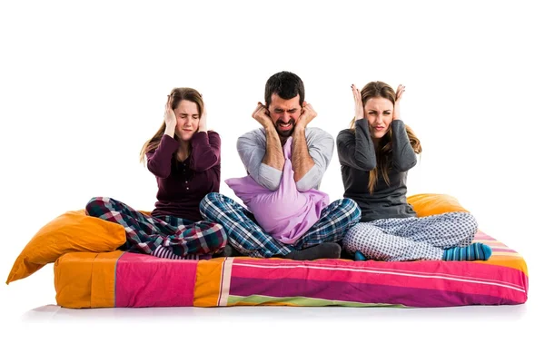 Tre amici su un letto che si coprono le orecchie — Foto Stock