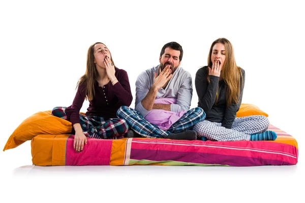 Tre amici su un letto sbadigliando — Foto Stock