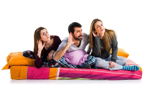 Trois amis sur un lit écoutant quelque chose — Photo