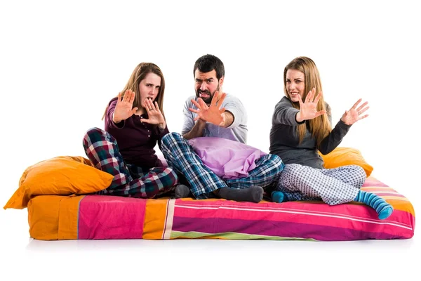 Tres amigos en una cama haciendo señal de stop — Foto de Stock