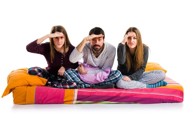 Tre amici su un letto che mostrano qualcosa — Foto Stock