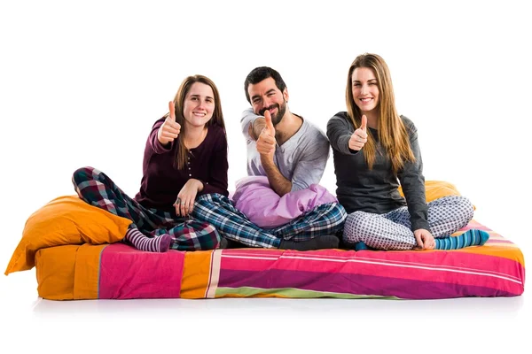 Tři přátelé na posteli s palcem nahoru — Stock fotografie