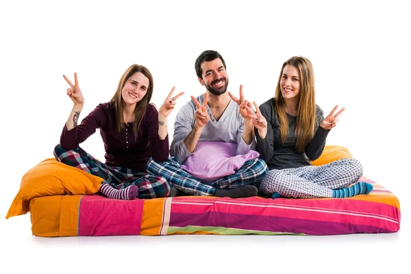 Tre amici su un letto che fanno il gesto della vittoria — Foto Stock