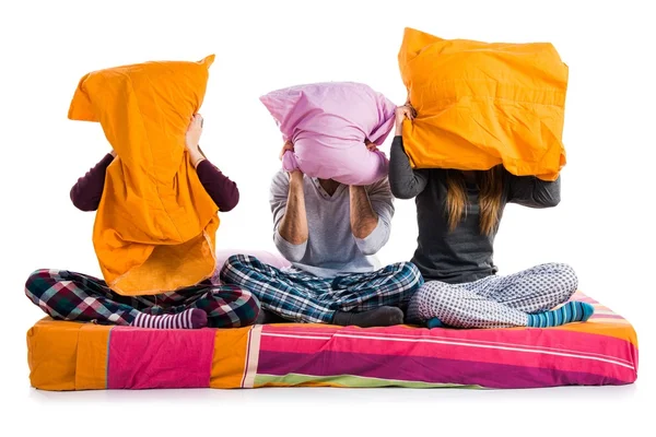 Tři přátelé na posteli, schovává se za jejich polštáře — Stock fotografie