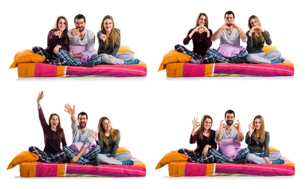 Bir yatak selamlayan üzerinde üç arkadaş