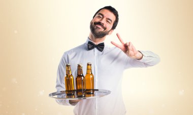 Garson bira şişeleri zafer jest yapıyor tepsi ile