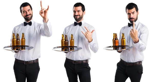 Garçom com garrafas de cerveja na bandeja fazendo gesto chifre — Fotografia de Stock