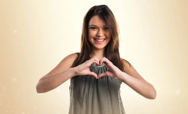 Young girl making a heart with her hands — Stock Photo, Image