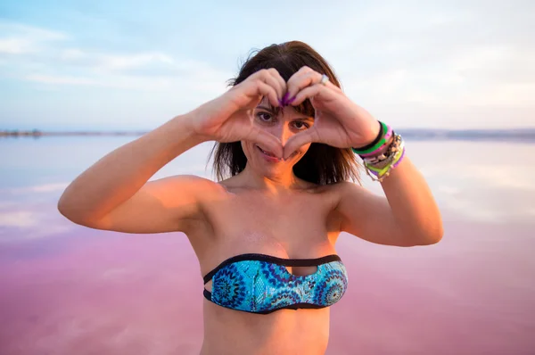 Wanita cantik di danau berwarna-warni membuat hati dengan tangannya — Stok Foto