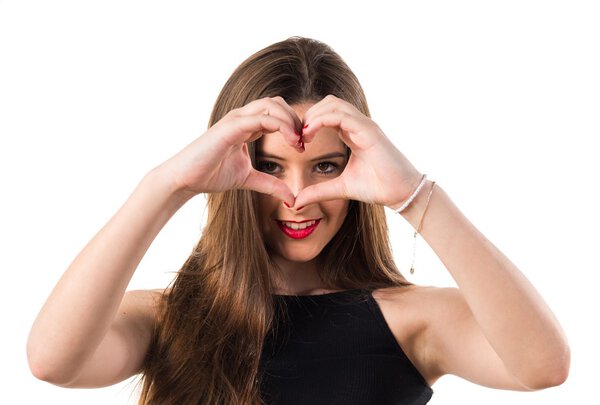 Молодая девушка делает сердце своими руками
