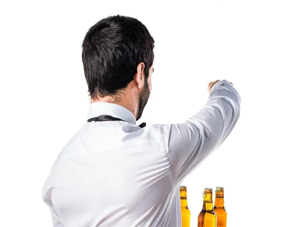 Serveur avec des bouteilles de bière sur le plateau pointant vers l'arrière — Photo