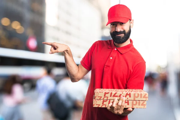 Rozvoz pizzy muž ukázal na bočních — Stock fotografie