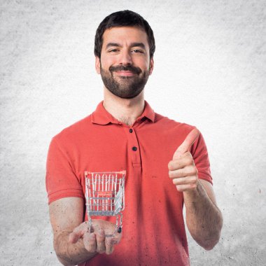 Yakışıklı adam başparmak ile bir süpermarket arabası oyuncak gidiyor