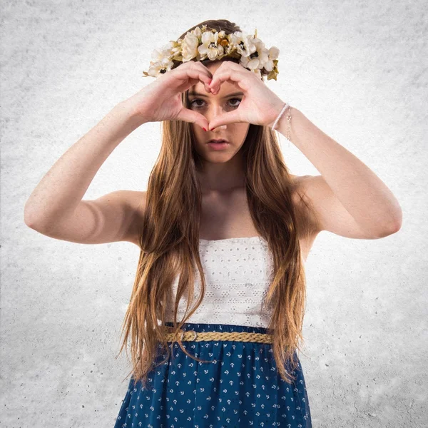 Girl with crown of flowers making a heart with her hands — Stock Photo, Image